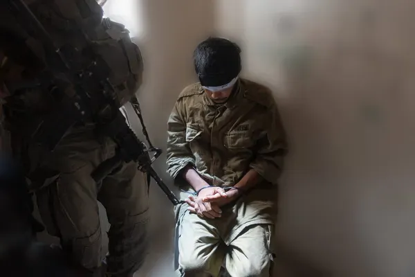 Ein Gazaner in IDF-Uniform, gefesselt und mit verbundenen Augen neben einem israelischen Soldaten in einem Haus in Rafah im vergangenen Monat. Das Foto wurde unscharf gemacht, um identifizierende Merkmale zu entfernen. Credit: David Bachar